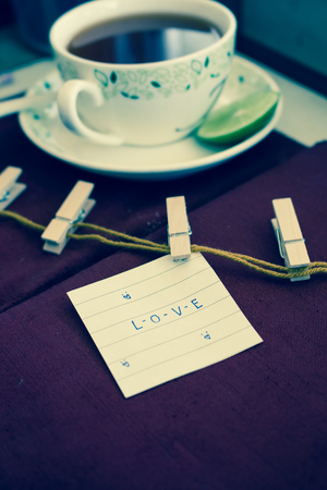 LOVE word clipped on paper with a cup of tea on the tableの写真素材
