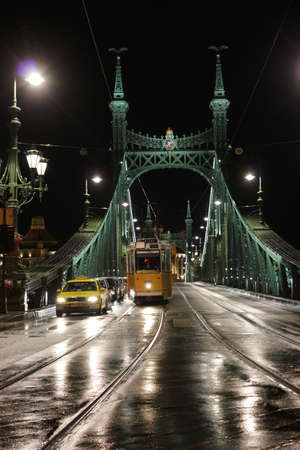 BUDAPEST, HUNGARY - December 15, 2017: yellow train and cars on illuminated Liberty Bridge or Freedom Bridge in Budapest, Hungaryのeditorial素材