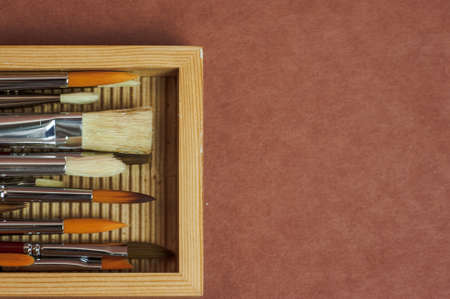 Brushes for the artist. Artistic brushes are placed in a professional case on a brown background. High quality photoの写真素材