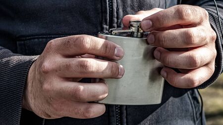 homeless fingers close up. hands of a dirty adult man. A homeless person is about to drink water from an aluminum flask.  の写真素材