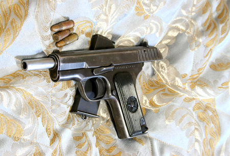 gun and bullets on a background of white fabric, close-up