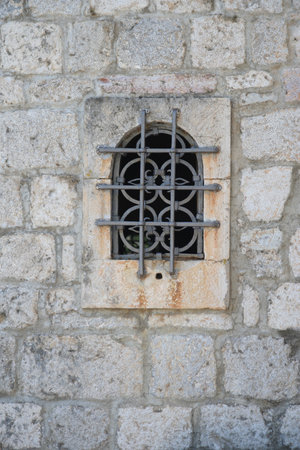 Old window on the stone wall of the old church in Montenegro