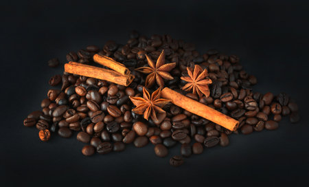 coffee beans with cinnamon and star anise on a black backgroundの写真素材