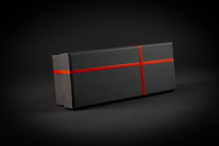 Black gift box with red ribbon on black background. 3d rendering
