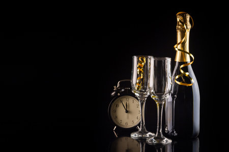 Champagne bottle, glasses and clock on black background with copy space. New Year and Christmas celebration concept.の写真素材