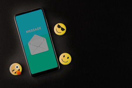 Smartphone with message notification on screen and smiley face on black background