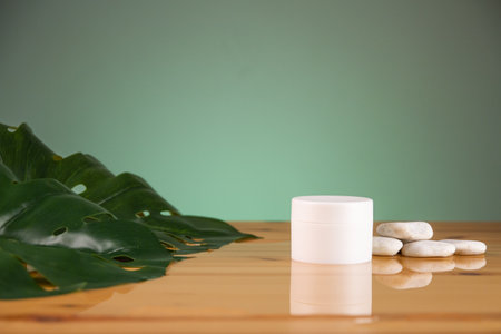Cosmetic cream bottle and green leaf on wooden table. Beauty and spa concept.の写真素材