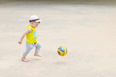 A little boy is playing football, the ball is flying. Active child in summer with a ballの写真素材