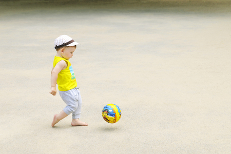 A little boy is playing football, the ball is flying. Active child in summer with a ballの写真素材
