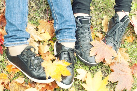 Two girls shoes on autumn leaves, top view, toned photo
