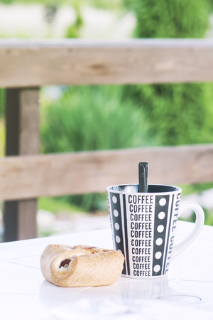 A coffee cup with a croissant on the table, a veranda of a country house, a toned photoの写真素材