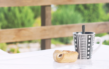 A coffee cup with a croissant on the table, a veranda of a country house, a toned photoの写真素材