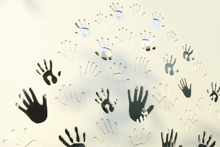 Handprints, adults and childrens palms make a natural pattern on a white wooden background. The concept of friendship and artの写真素材