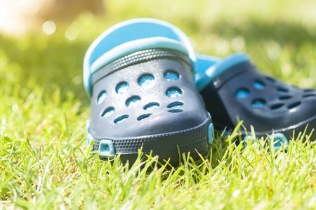Childrens blue slippers on the green grass in the garden, shoes for children, beach fashion for kids, a concept of relaxationの写真素材