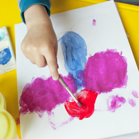A boy paints a drawing on a piece of paperの写真素材
