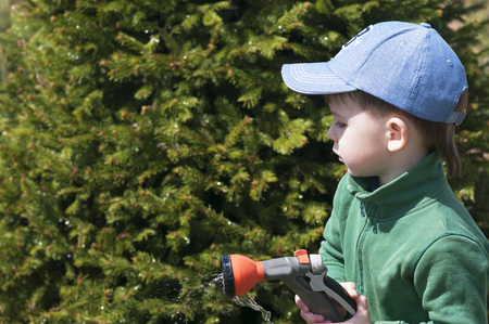 A child, a boy, watering a rubber hose in a garden, a country house, wateringの写真素材