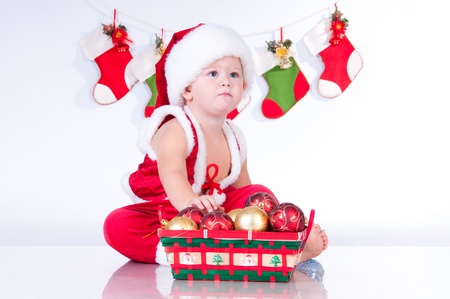Cute baby Santa Claus with garlands and a basket of Christmas toysの写真素材