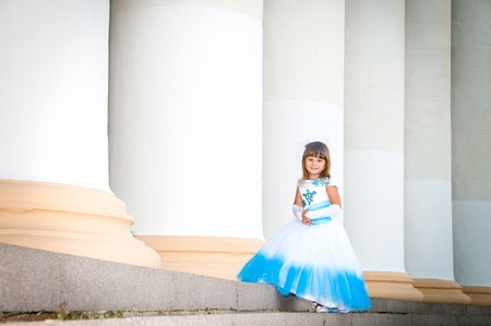 Little bride. A girl in a lush white and blue wedding dress and hat with nettingの写真素材