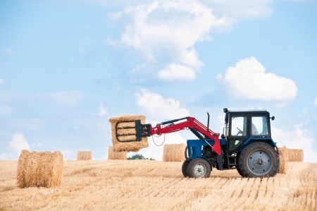 Tractor collecting round bales of straw の写真素材