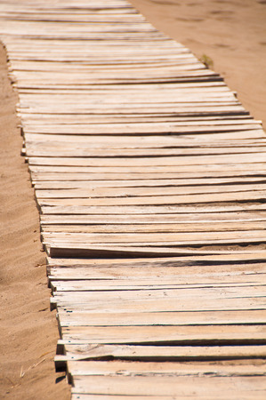 Old wooden bridge on the sandy shoreの写真素材