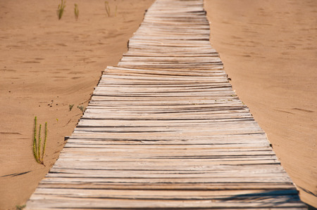 Old wooden bridge on the sandy shoreの写真素材