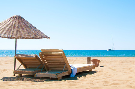 Sunbeds and rattan parasols on sandy seaside.の写真素材