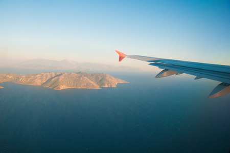 View from the airplane over the sea, the mountains, the wingの写真素材