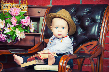 Little boss. Baby gentleman sitting in a leather chair in the hatの写真素材