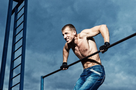 Athlete doing pull-up on horizontal bar. Mans fitness at the stadium