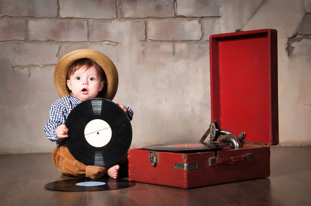 Funny baby boy in retro hat with vinyl record and gramophoneの写真素材