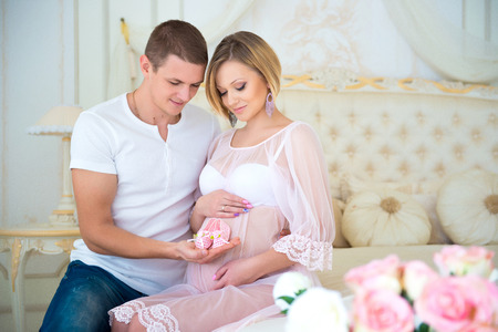 Happy Pregnancy: husband holding baby booties near the belly his pregnant wife