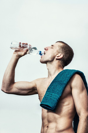 Muscular young man after a workout  drinking  bottle of waterの写真素材