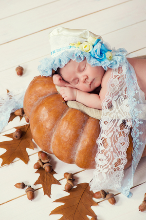 Tale of Cinderella. Little beautiful newborn baby girl in a bonnet sleeping on a pumpkinの写真素材