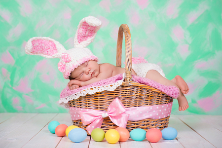 Newborn baby girl in a rabbit costume has sweet dreams on the wicker basket. Easter Holidayの写真素材