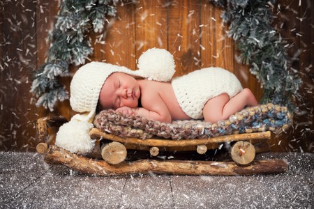 The baby is sleeping in wooden sledges. New year's Eve.の写真素材