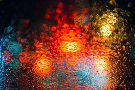Rain drops on window with street bokeh lights, colorful street lights