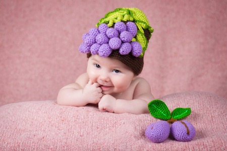 Newborn baby in a knitted cap in the form of grapes.の写真素材