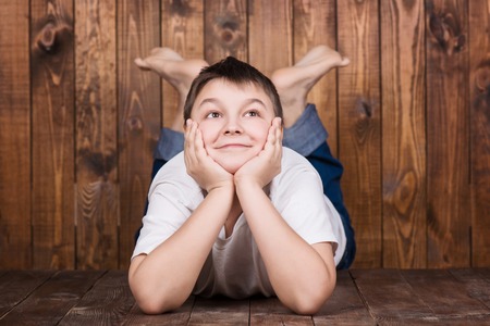 Teenager lying on his stomach. Against the background of the wooden planks.の写真素材