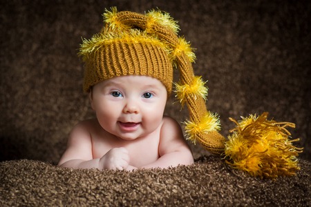 Newborn in a knitted winter hat on a beige background.