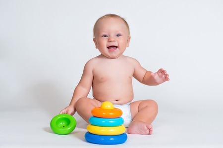 smiling child baby playing with color pyramid toy isolated.の写真素材