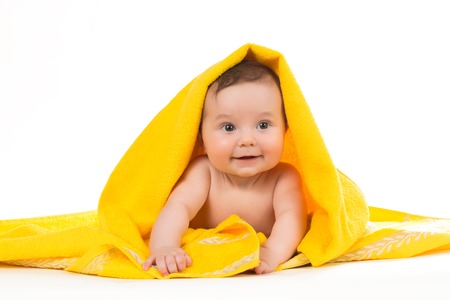 Newborn baby lying down and smiling in a yellow towelの写真素材