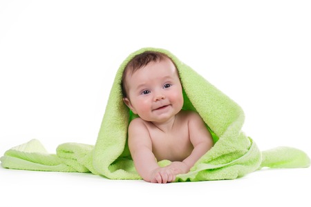 Newborn baby lying down and smiling in a green towel.の写真素材
