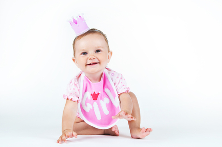 Girl with a crown, sitting in a bib on a white background.の写真素材