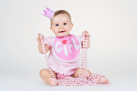 Girl with a crown, sitting in a bib on a white background.の写真素材