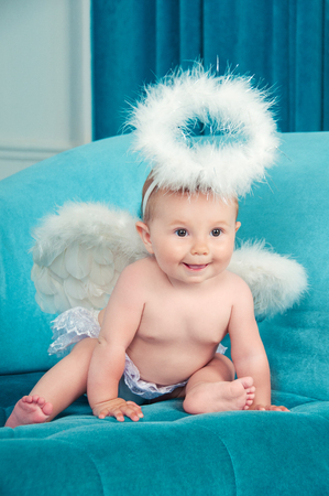 Little angel smiling and happy sitting on the couch.の写真素材