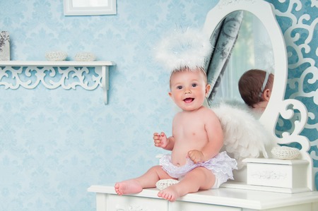 Little angel smiling and sitting on the dressing tableの写真素材