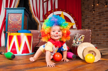 Little baby clown with red nose multi-colored wig in with ballsの写真素材