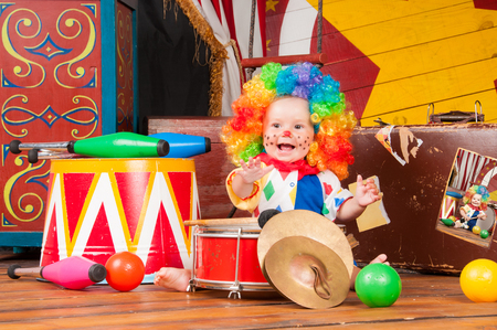 Little baby clown with red nose multi-colored wig in with ballsの写真素材