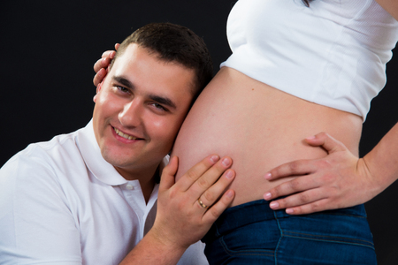 9 months. Pregnant couple awaiting the birth of a son. Black background.の写真素材