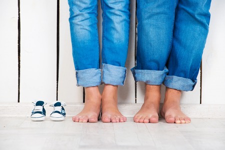 Waiting of baby. Pregnant woman, pregnancy, motherhood. Happy family. Moms, Dads and babys bootees. Family lookの写真素材